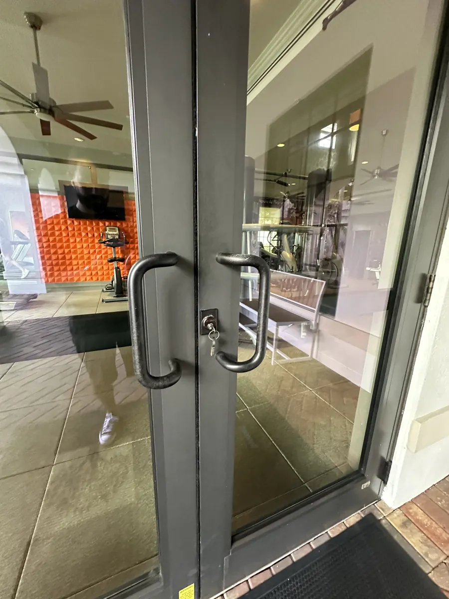 Glass double entry doors with pull handles and keyed cylinder at a Miramar gym